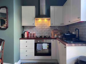 a kitchen with white cabinets and an oven at Spacious Georgian Apartment - Central Frome in Frome