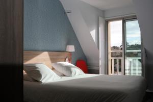 ein Schlafzimmer mit einem Bett und einem großen Fenster in der Unterkunft Hôtel Beau Soleil in Pornic