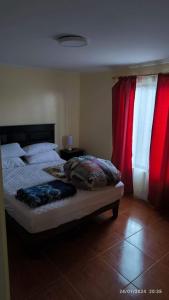a bedroom with a bed and red curtains at Cabaña Lomas del mar - Papudo in Los Corrales