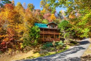 a house with a green roof in the woods at Bears Corner w/ Hot Tub, Arcade & Community Pool! in Gatlinburg