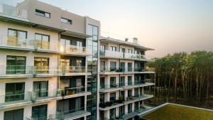 un immeuble d'appartements avec balcon et arbres dans l'établissement Resort Hevenia Mrzeżyno 4, à Mrzeżyno