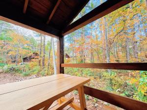 a wooden bench in a cabin with a large window at Forestalk House in Nagano