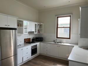 een keuken met witte kasten en roestvrijstalen apparaten bij Saltwater Bungalow - WiFi in Robe +6 foto's