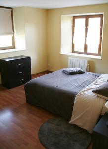 a bedroom with a bed and a dresser and two windows at Apartment Au Calme in Munster