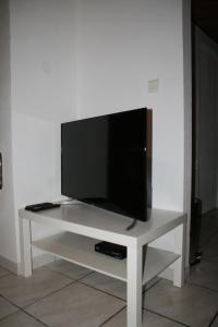 een flatscreen-tv zittend op de top van een witte tafel bij Apartment Au Calme in Munster