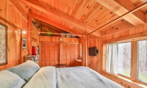 ein Schlafzimmer mit einem Bett in einem Holzzimmer in der Unterkunft 4 Bedroom Log Cabin with Stream and Great Location in Lanesville