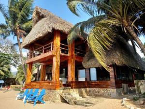 - un bâtiment sur la plage avec des chaises et des palmiers dans l'établissement Hotel Guapinol, à Marisco Guapinol 23 autres photos