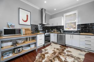 a kitchen with white cabinets and a rug at Dalton Cottage - Charm & Convenience in Orange