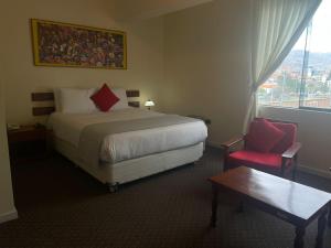 a hotel room with a bed and a red chair at Hotel Cienciano in Cusco