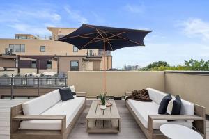 a patio with two white couches and an umbrella at 3BR Luxury LoHi Townhome Rooftop Views Sleeps 6 Family in Denver