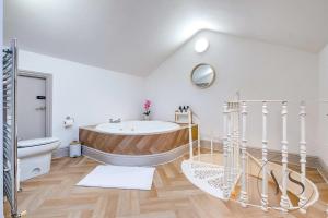a white bathroom with a tub and a toilet at 4BR Family Home in 89 Highgate with Jacuzzi, Games Room & Free Parking Near Birmingham in Walsall +112 photos