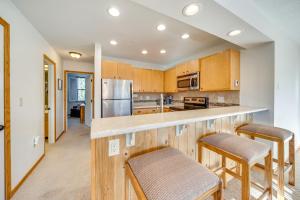 a kitchen with wooden cabinets and a counter with stools at 2 Mi to Winter Park Resort: Condo w/ Pool Access! in Winter Park