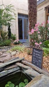 a garden with a pond with a sign and flowers at Les Pénates de Loire in Ancenis