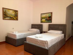 two beds in a room with paintings on the wall at Haxhialiu Villa in Berat