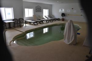 una piscina en una habitación con sillas y mesas en Best Western Oasis Inn, en Canadian