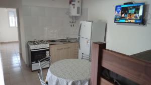 a kitchen with a white refrigerator and a tv on the wall at Complejo El Descanso in San Antonio Este