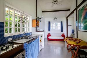 uma cozinha com um lavatório e um sofá num quarto em Sol-lua Bangalo com uso exclusivo da piscina em Ilhabela