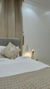 a bed with a pillow and a lamp on a table at نزل العلا in AlUla