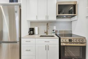 a kitchen with white cabinets and a stainless steel refrigerator at ULTRA spacious apartment steps from the beach in Hollywood