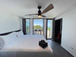 a bedroom with a white bed with a ceiling fan at Yunque Reserve Secluded Rainforest House in Hato Candal +25 photos