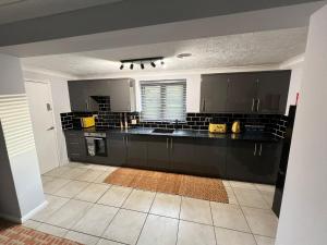 a large kitchen with black cabinets and a tile floor at Little Edgewood in Norwich