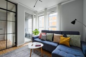 salon z niebieską kanapą i kolorowymi poduszkami w obiekcie UrbanNestapartments-Op51 w mieście Katowice