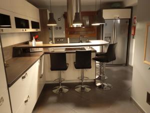 une cuisine avec un îlot doté de tabourets de bar noirs dans l'établissement Cottage champêtre, à Marmoutier