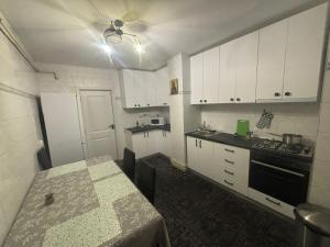 a small kitchen with white cabinets and a table at Apartament City Center Craiova in Craiova