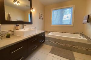a bathroom with a sink and a tub and a mirror at Cozy Riverside Cottage Escape with SPA, Pool Table and Dock Access in Rigaud +26 photos