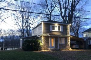 a house with lights on the front of it at Cozy Riverside Cottage Escape with SPA, Pool Table and Dock Access in Rigaud