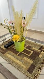 a green vase with flowers sitting on a rug at 2A Estepa Apart-centro costanera in Comodoro Rivadavia +33 photos