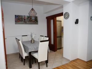 a dining room with a table and chairs and a clock at Iva Lux stan na dan in Banja Luka