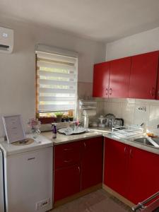 cocina con armarios rojos y fregadero blanco en Apartman Kutak, en Šipovo 9 fotos más