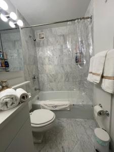 une salle de bain blanche avec toilettes et baignoire dans l'établissement Nomad stylish studio in NYC, à New York