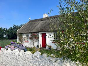 a small white house with a red door at Clannad Cottage in Arboe