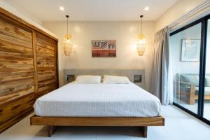 a bedroom with a bed and two pendant lights at Ohana Villas in Santa Teresa Beach