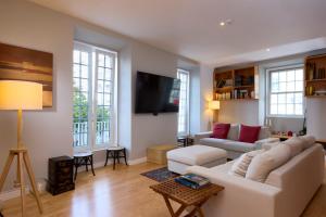 a living room with a white couch and a tv at Matriz 55 in Ponta Delgada