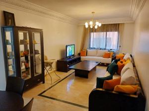 a living room with a couch and a tv at Family Apartment with Pool in Marrakech