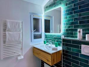 a green tiled bathroom with a sink and a mirror at Le Vertueux - CDG - Parking - Confort - Wifi in Louvres