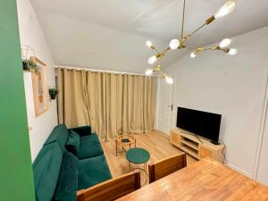 a living room with a green couch and a table at Le Vertueux - CDG - Parking - Confort - Wifi in Louvres
