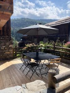 ein Tisch und Stühle mit einem Sonnenschirm auf einem Deck in der Unterkunft Chalet Furz'a - Chalet Familial Cosy à Méribel MAE-7811 in Les Allues