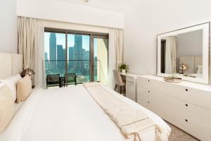 een witte slaapkamer met een groot bed en een groot raam bij Prime Retreats @ Burj Royale By Emaar in Dubai +77 foto's