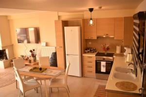 a kitchen with a table and chairs and a white refrigerator at Alia Beachfront Penthouse with Sea View in Lefkandi Chalkidas