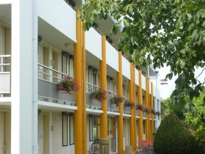 un grand bâtiment blanc avec colonnes jaunes dans l'établissement Premiere Classe Strasbourg Ouest, à Strasbourg