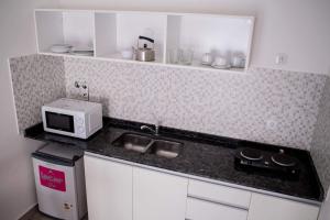 a kitchen with a sink and a microwave on a counter at Apart Valeria cerca del Mar in Valeria del Mar