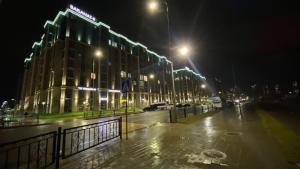 a wet city street at night with buildings and lights at Байсанат in Karagandy