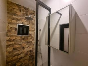 een badkamer met een glazen douchedeur en een stenen muur bij Parakreek Apartments in Boxel +17 foto's