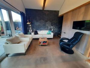 Una sala de estar con un sofá blanco y una silla. en Vakantievilla 10 km van strand honden welkom omheinde tuin sauna buitenbad, en Dirkshorn