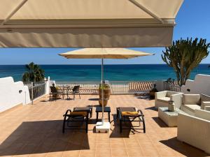 a patio with chairs and an umbrella and the ocean at Miramar3, Costa Calma, traumhafter Meerblick, max 2 Pers in Costa Calma