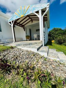 a patio with a blue and white umbrella on a house at Soleil Levant - Vue mer Imprenable in Le Robert +3 photos